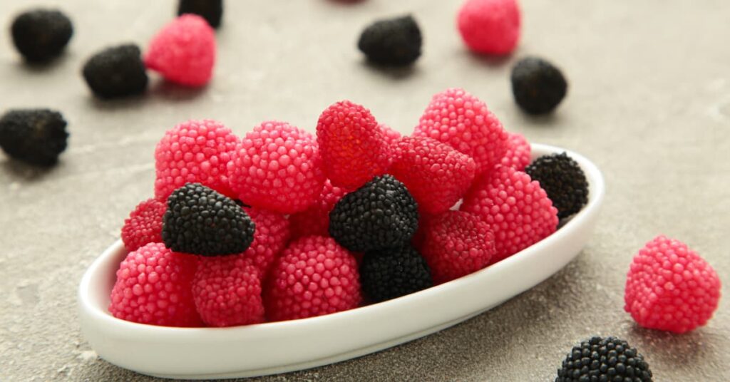 Moras de gominola rojas y negras en un cuenco blanco, ejemplo de tipos de moras de gominola con cobertura de bolitas de azúcar.